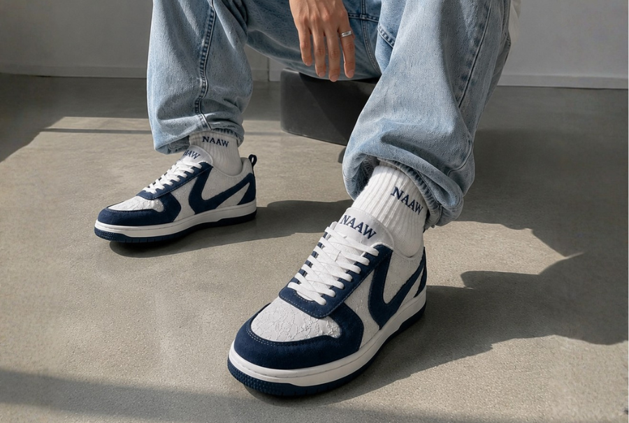 Navy and white NAAW sneakers worn with light blue jeans on concrete