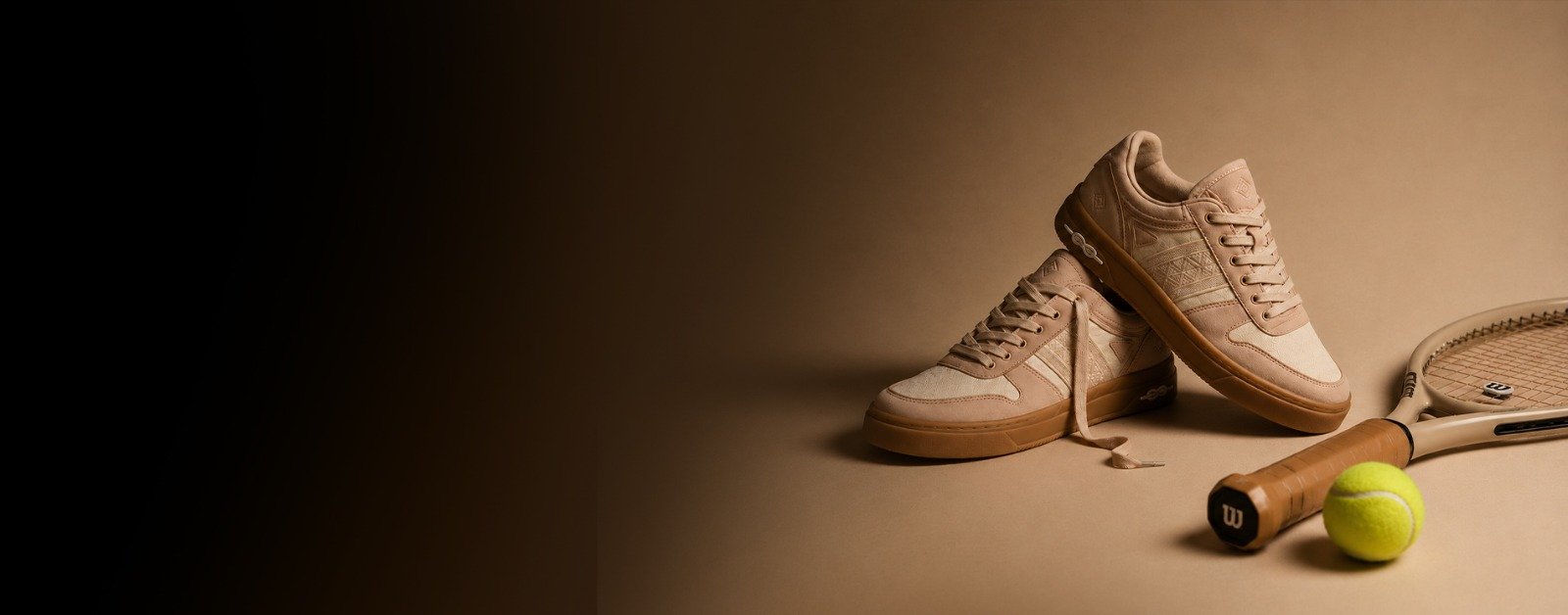 Tan NAAW sneakers lit against a dark background with a tennis ball and racket